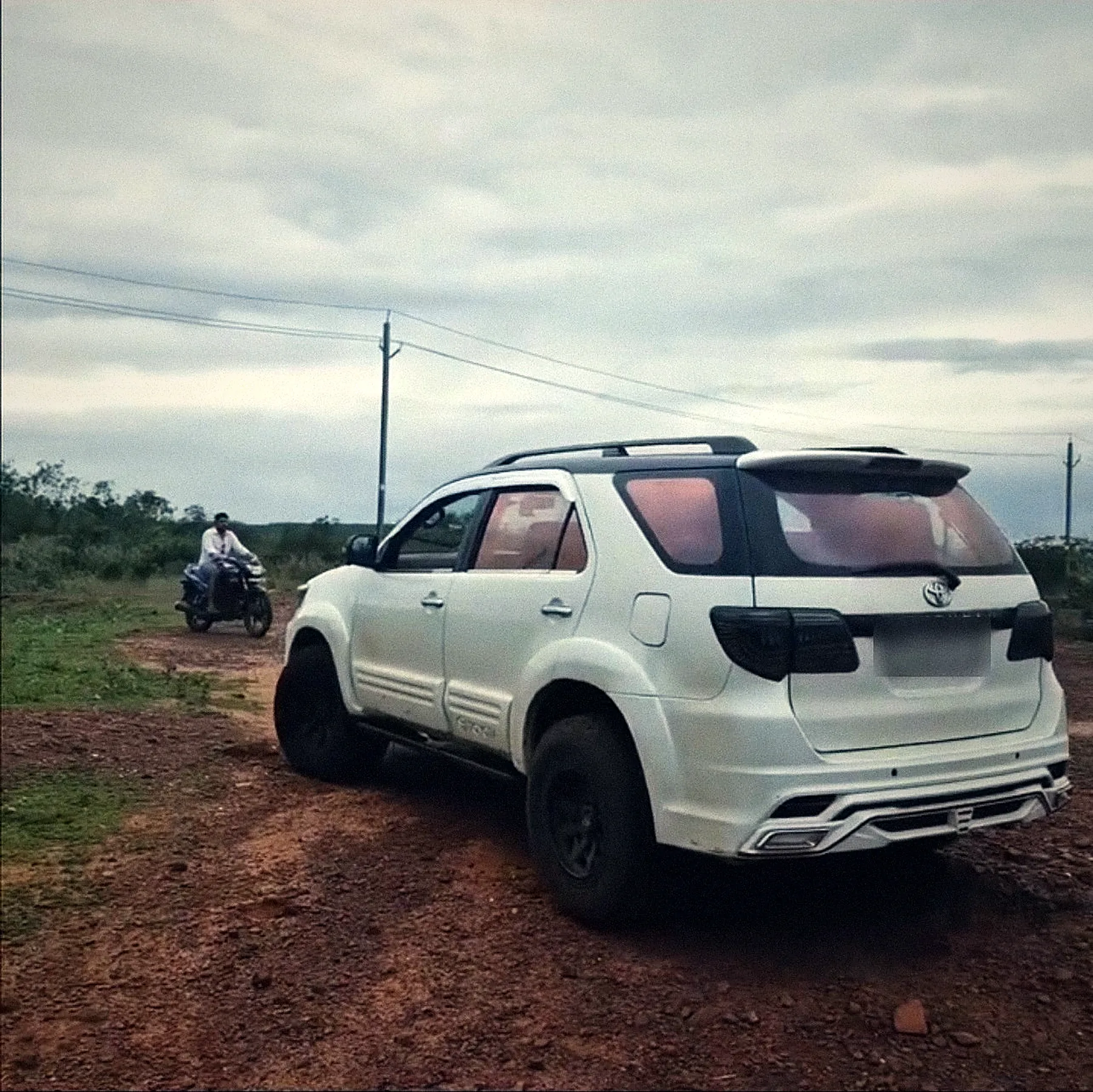 The white Fortuner on a red-dirt track