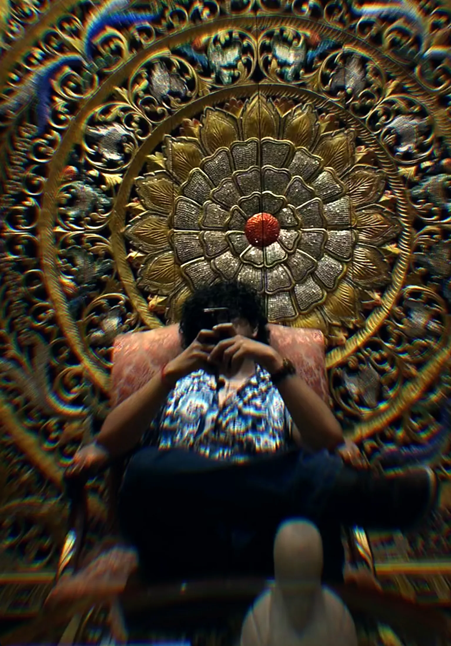 Bhumani seated in front of a huge carved golden wheel