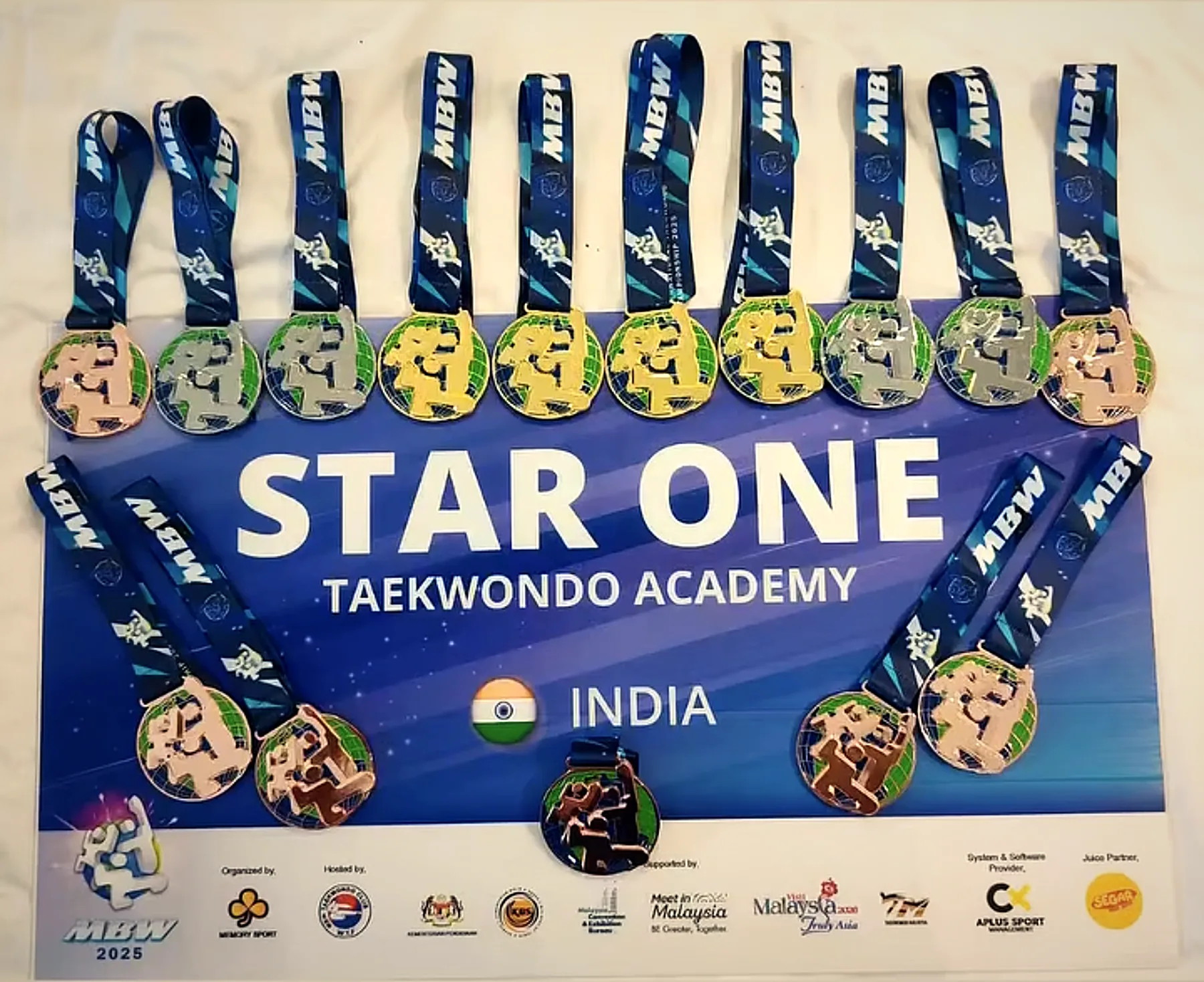 MBW 2025 medals laid out on a Star One Taekwondo Academy India banner